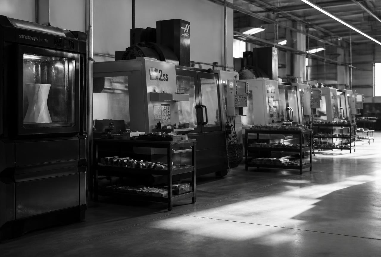 Reparto produttivo con macchine CNC e stampanti 3D, fotografia in bianco e nero